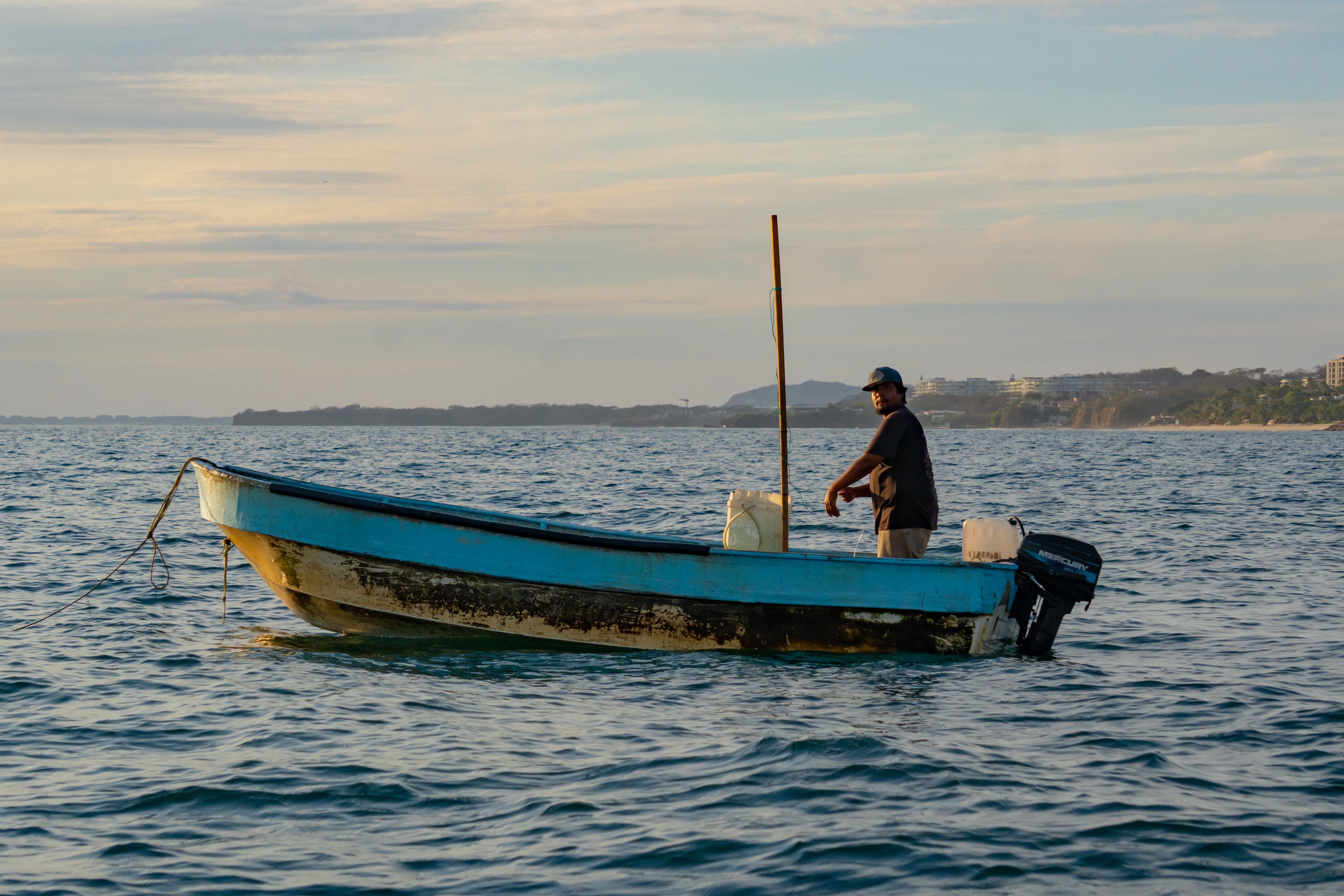 Pescador de pie en barco azul